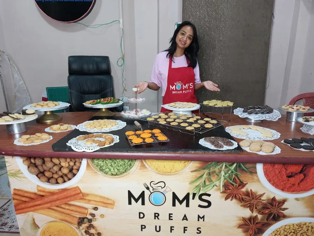 a student in a baking class presenting a table full of various baked items made by her