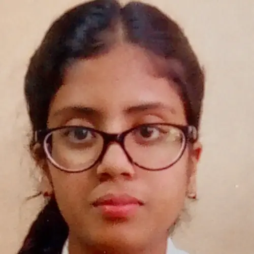 A close-up portrait of a young woman with dark hair wearing black-framed glasses and a white collared shirt, looking directly at the camera against a plain light background.